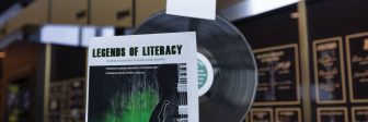 Program with guitar on the cover propped up against a vertical vinyl record with plaques in the background